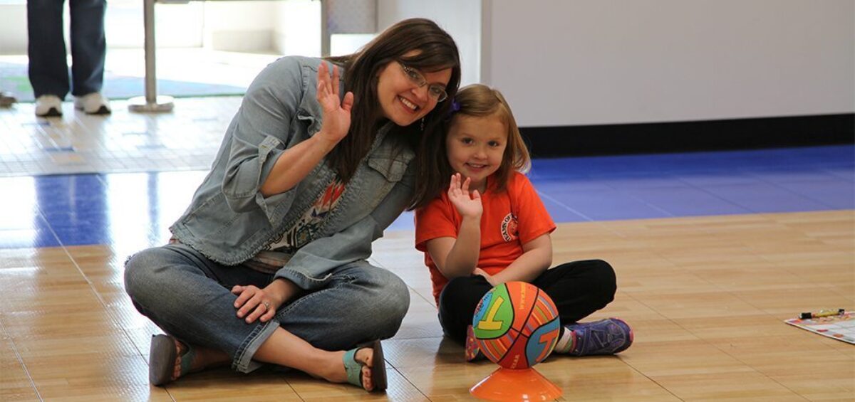 A mom and a child basketball player waving.