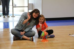 A mom and a child basketball player waving.